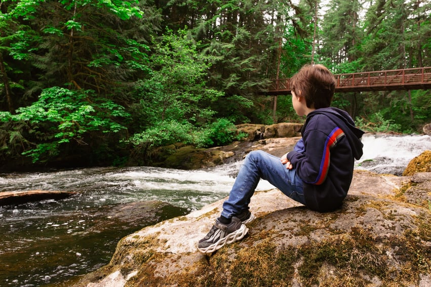 boy sitting on rock at lacamas regional park